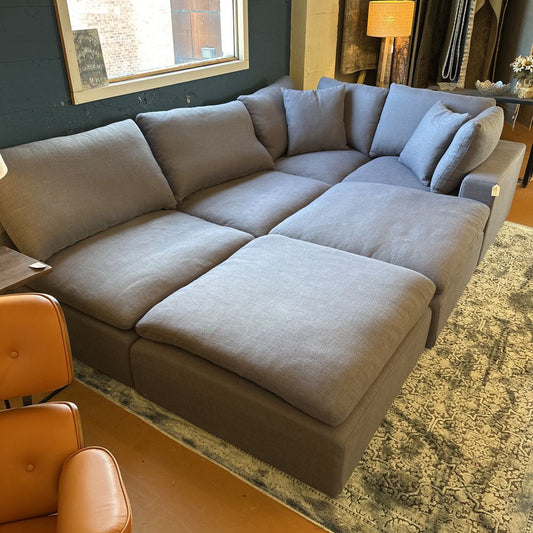 Gray sectional sofa in a living room with a lamp and chair.