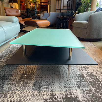 Modern coffee table with green glass top in a living room setting