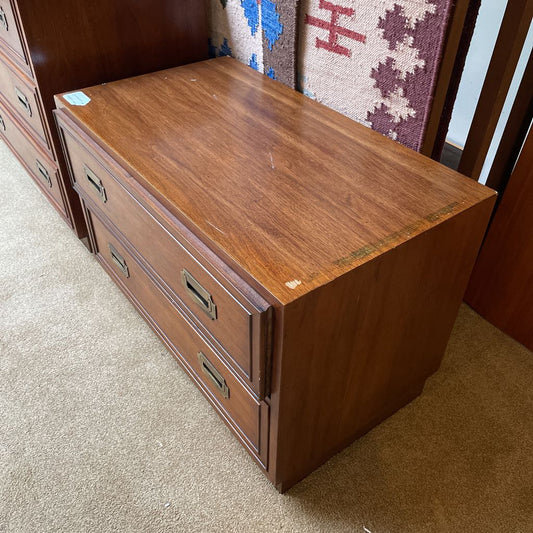 Wooden dresser with multiple drawers on a carpeted floor.