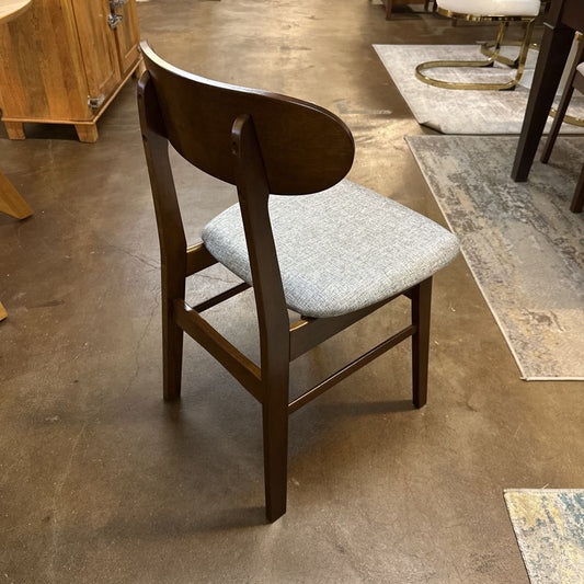 Wooden chair with a gray cushion on a concrete floor.