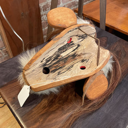 Wooden horse toy with fur on a wooden surface