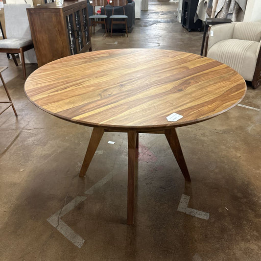 Wooden dining table in a showroom setting with furniture in the background