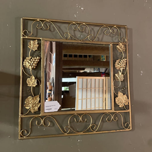 Decorative gold-framed mirror on a plain wall