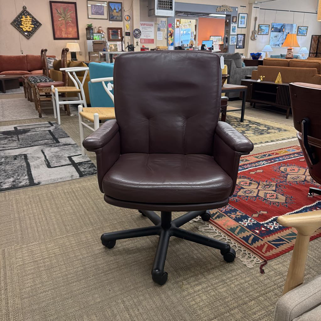 Brown leather office chair in a room with multiple chairs and rugs.