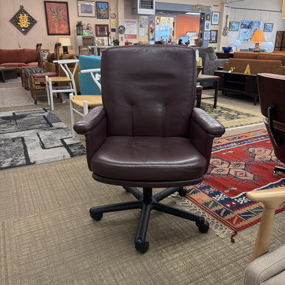Brown leather office chair in a room with multiple chairs and rugs.
