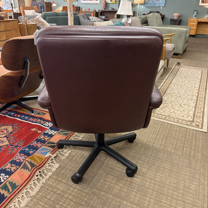 Brown office chair in a furniture store setting with various chairs and a rug.