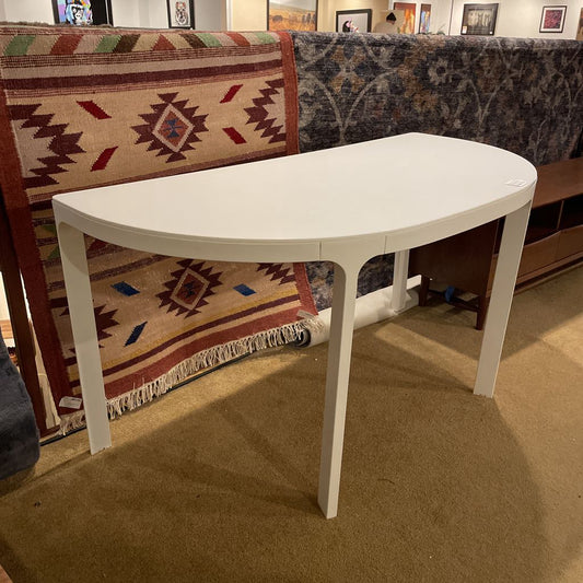 White oval table in a room with patterned rug and sofa