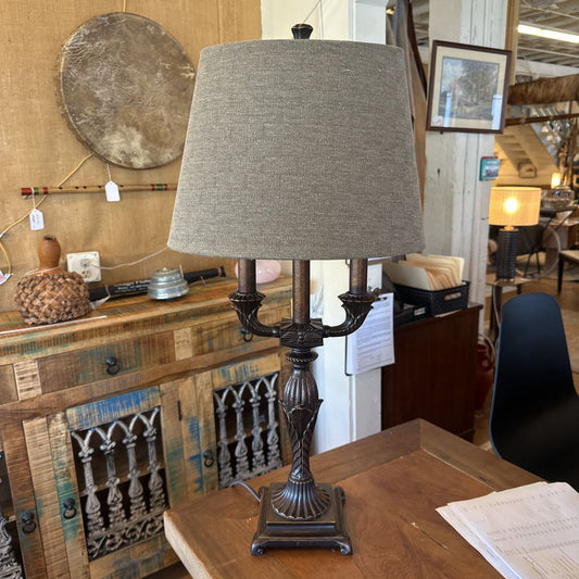 Decorative lamp with a gray shade on a wooden surface in an indoor setting.
