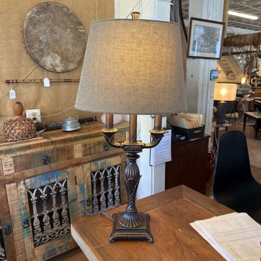 Decorative lamp on a wooden table with rustic furniture and wall art in the background