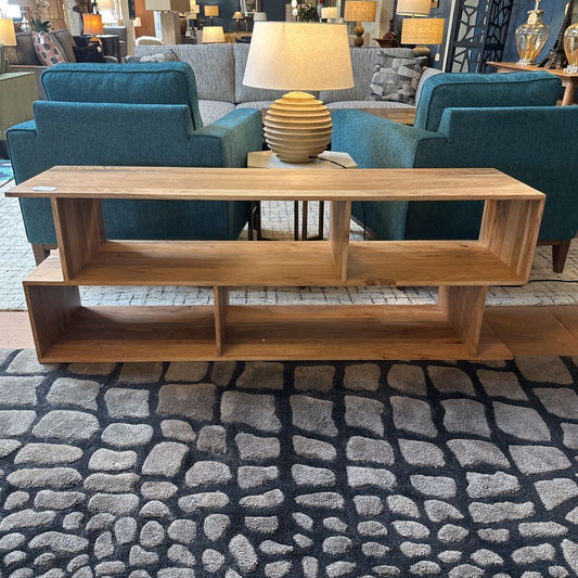 Wooden coffee table with a lamp on it, surrounded by teal chairs and a gray sofa in a room setting.