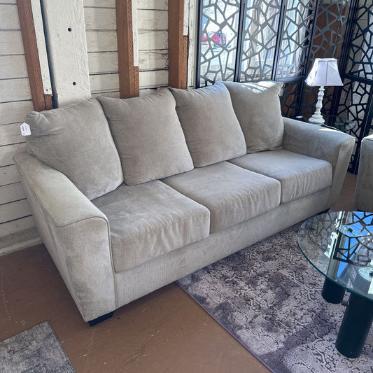 Beige sofa in a room with a glass table and decorative elements.