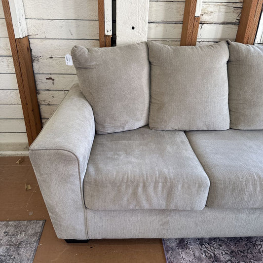 Gray sofa with cushions against a wooden wall.