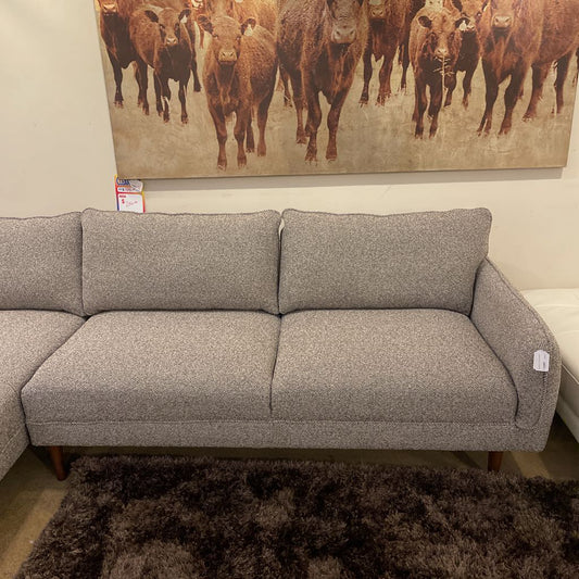 Gray sectional sofa in a room with a painting of cows on the wall.