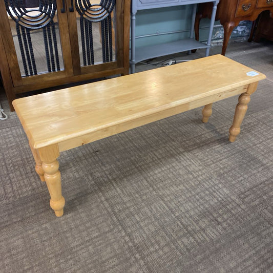 Wooden bench on a carpeted floor with furniture in the background
