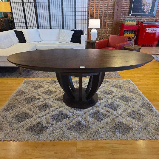 Wooden dining table in a living room setting with a sectional sofa and decorative items.