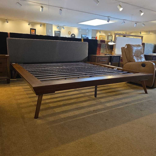 Wooden bed frame with mattress in a showroom setting