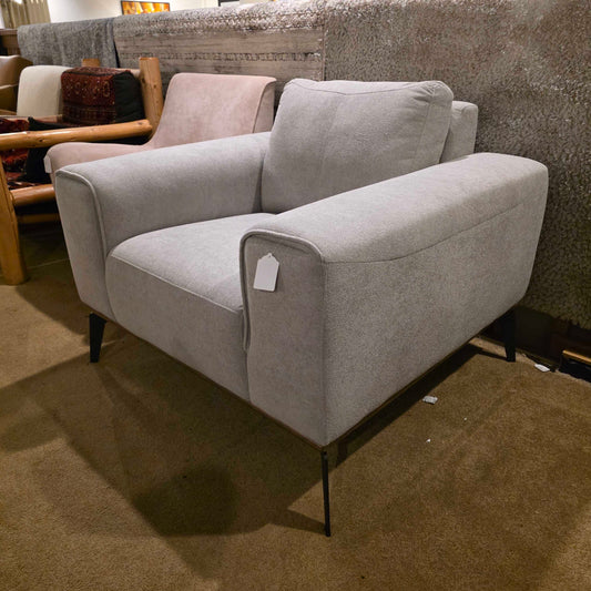 Gray recliner chair in a room with a textured wall and wooden floor.