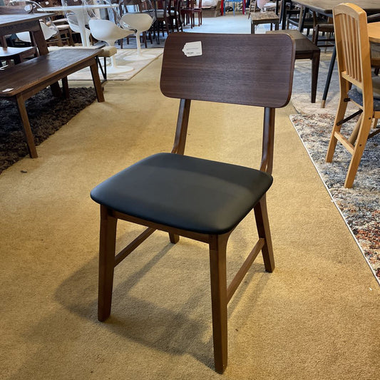 Wooden chair with black cushioned seat in a room with carpeted floors and other furniture.