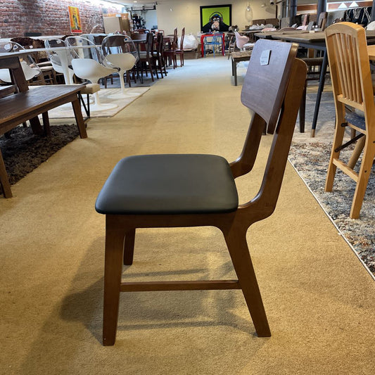 Wooden chair with a black seat in a showroom setting