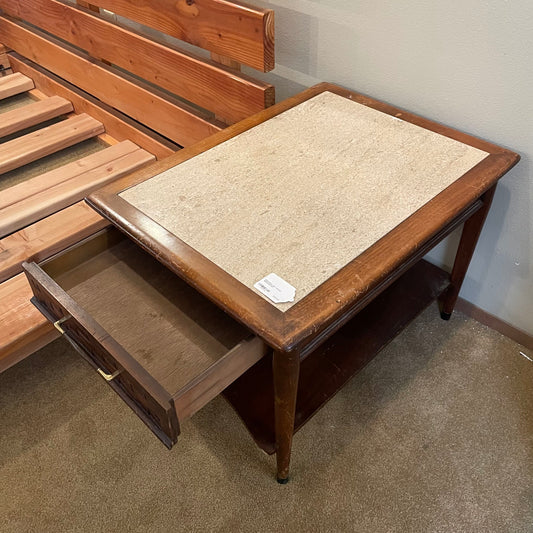 Wooden bed with an attached side table and drawer in a room setting.