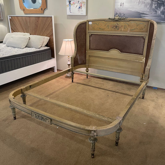 Vintage-style bed frame in a showroom setting with other furniture.
