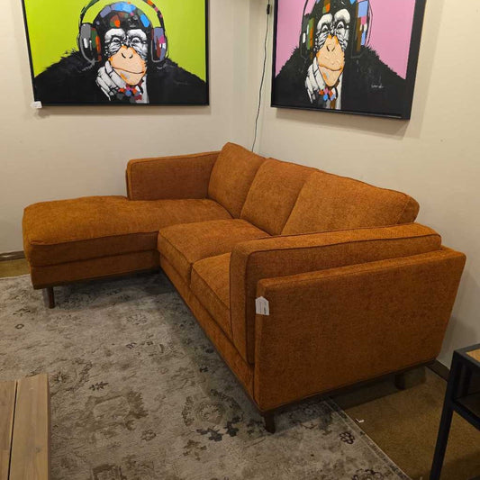 Orange sectional sofa in a room with colorful monkey artwork on the walls.