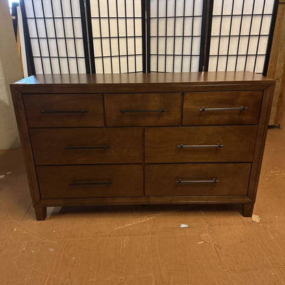 Wooden dresser with four drawers in front of a black and white patterned screen.