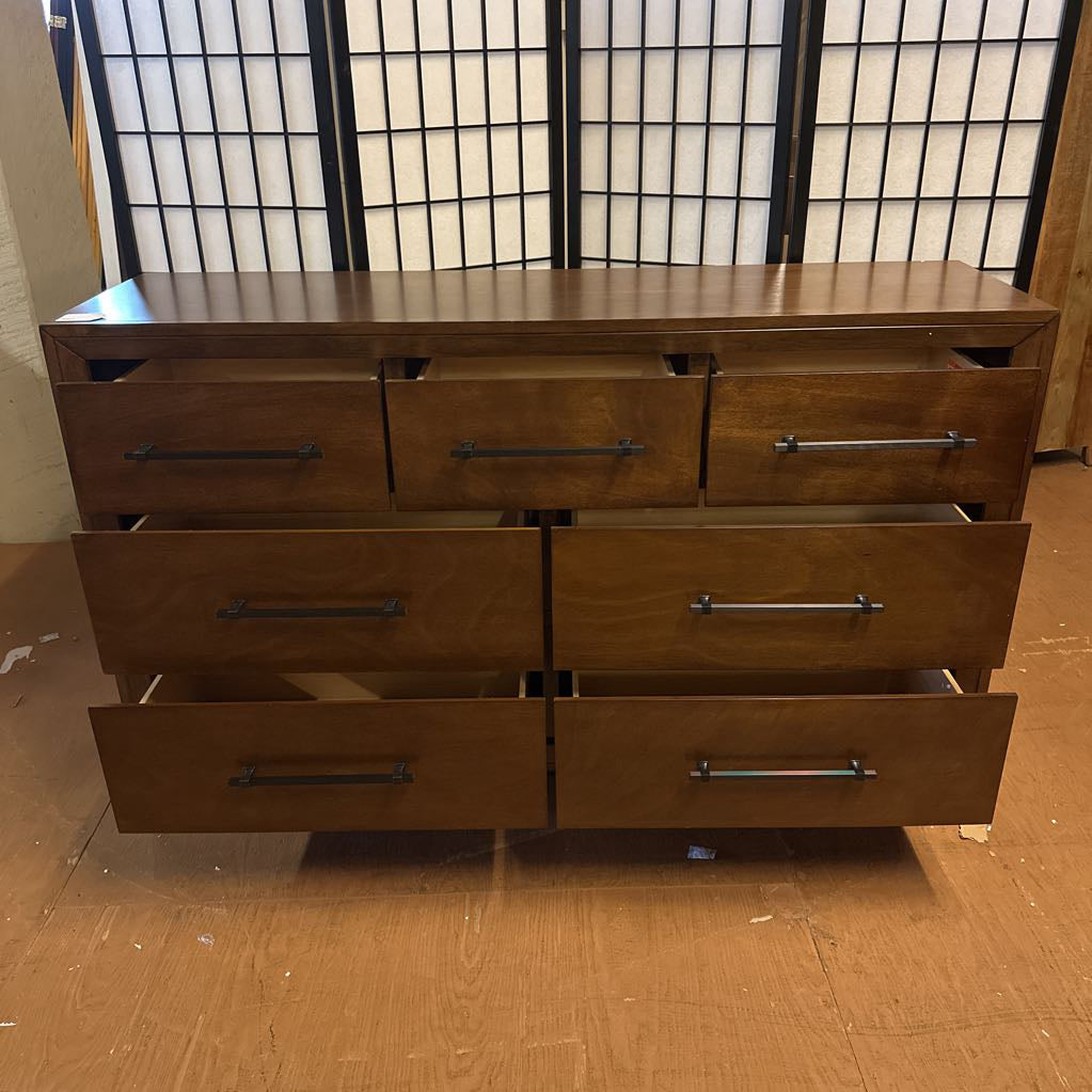 Wooden dresser with six drawers in a room with a window in the background