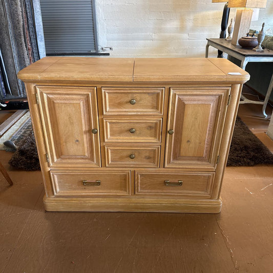 Wooden cabinet with multiple drawers and doors in a room setting.