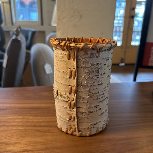 Cylindrical ceramic vase with textured surface on a wooden table