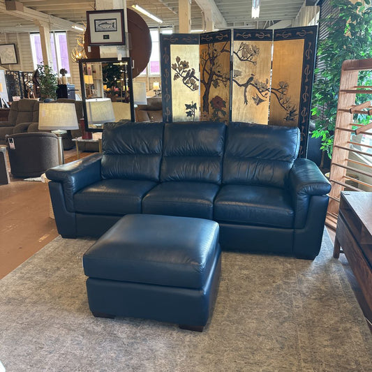 Blue leather sofa and ottoman in a showroom setting with decorative elements.