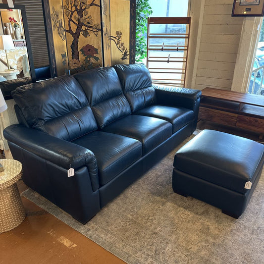 Blue leather sofa with matching ottoman in a room setting.