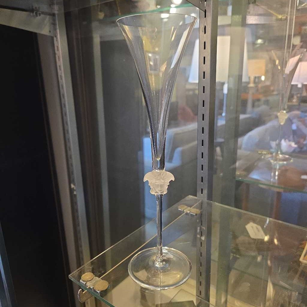 Clear glass goblet with decorative base on a glass display case.