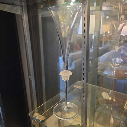 Clear glass goblet with decorative base on a glass display case.