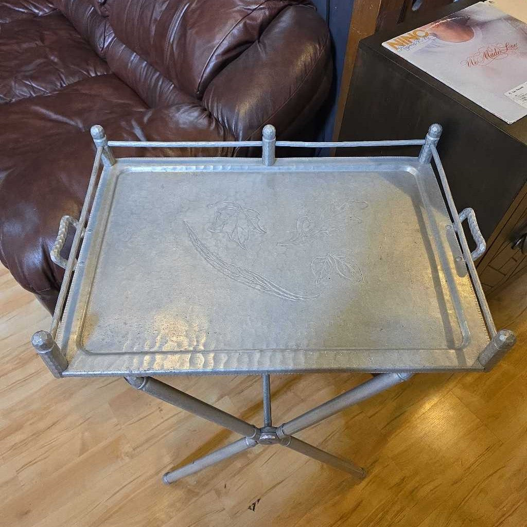 Metal tray on a wooden floor next to a brown leather couch