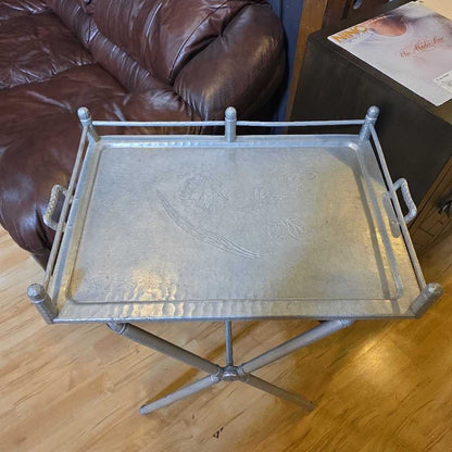 Metal tray on a wooden floor next to a brown leather couch