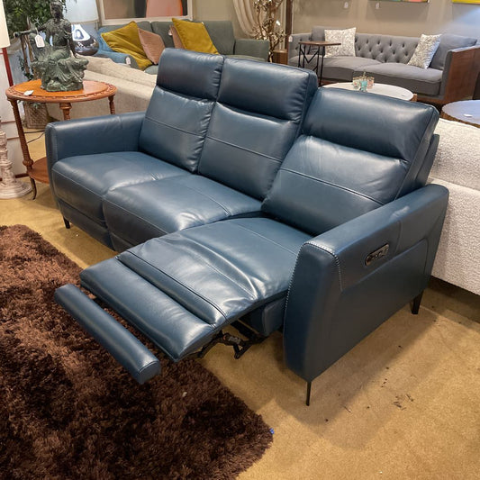 Blue leather recliner sofa in a showroom setting with other furniture.