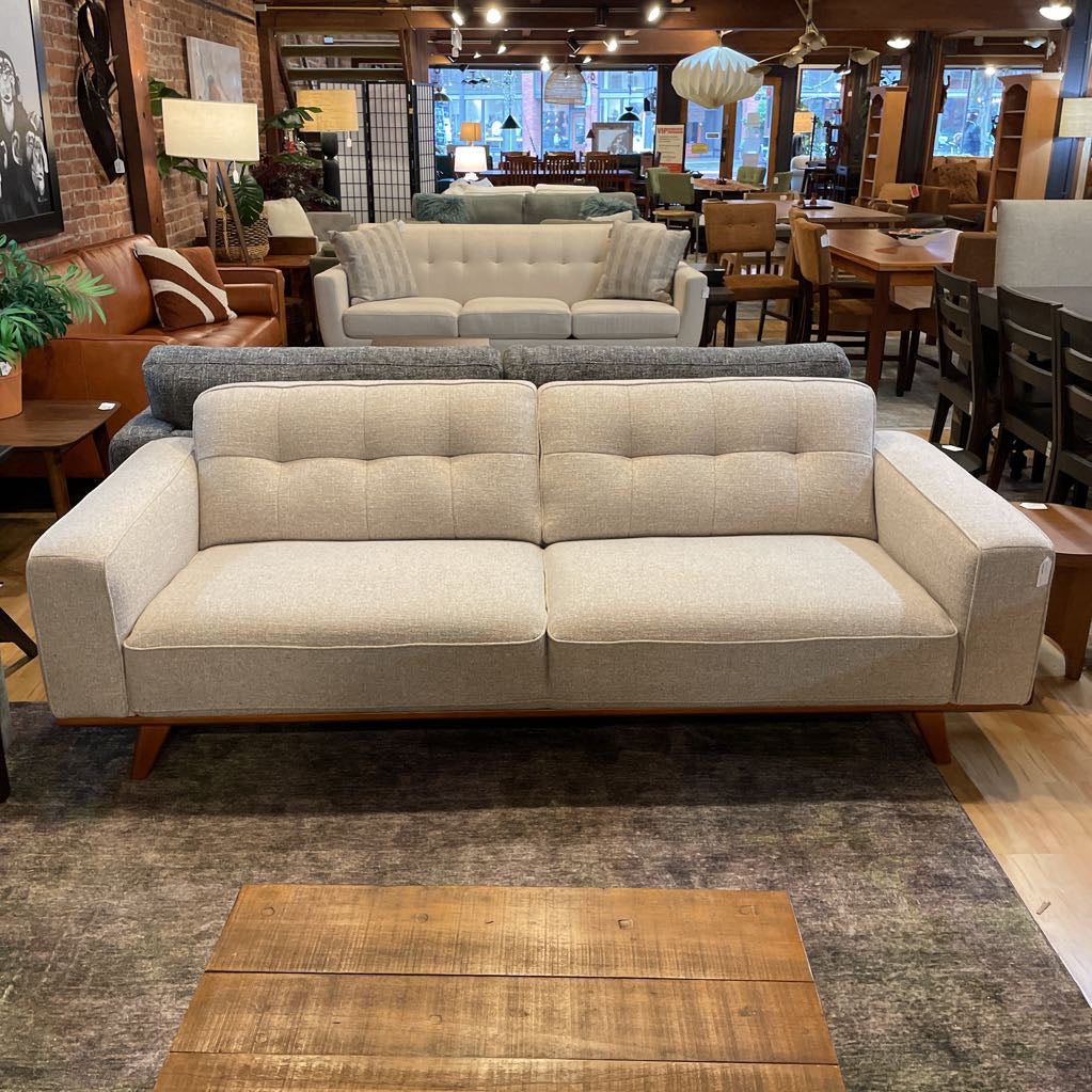 Beige sofa in a furniture store with various seating options and decor.