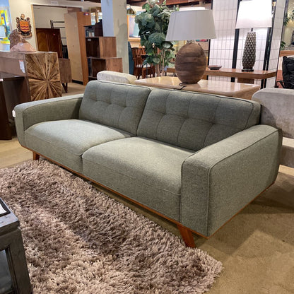 Gray sofa in a showroom setting with other furniture and decor items.