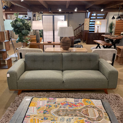 Gray sofa in a showroom with various furniture and decor items.