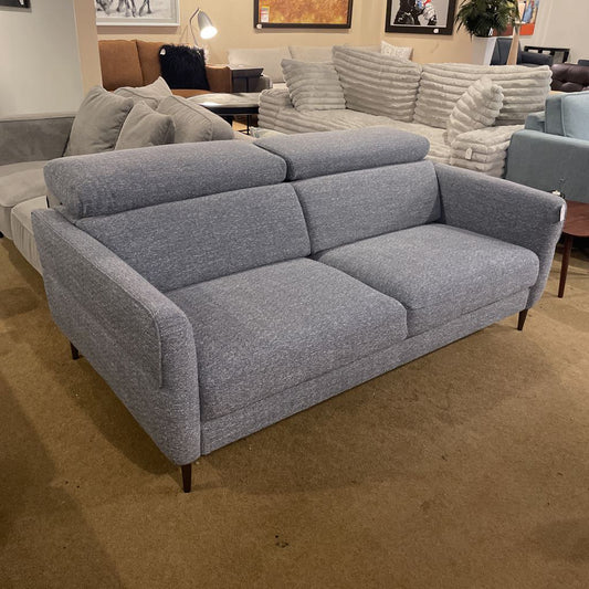 Gray sofa in a showroom setting with other furniture in the background