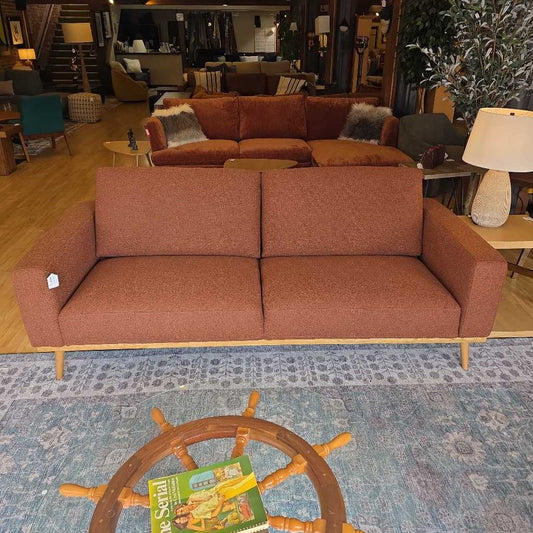 Brown sofa in a store setting with a rug and small table in front