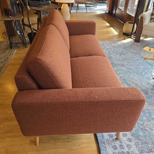 Brown sofa in a room with wooden floor and rug