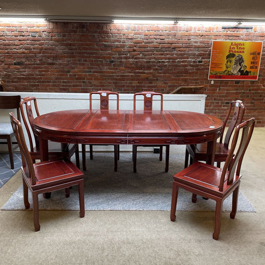 Wooden dining table with chairs in a room with brick walls and a poster on the wall.