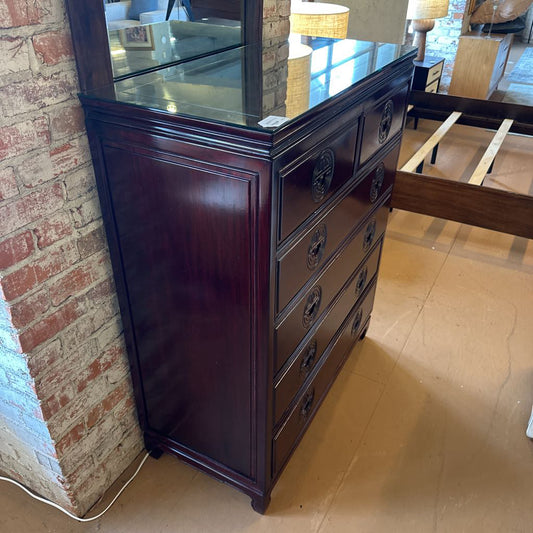 Dark wood dresser against a brick wall in a room with wooden flooring.