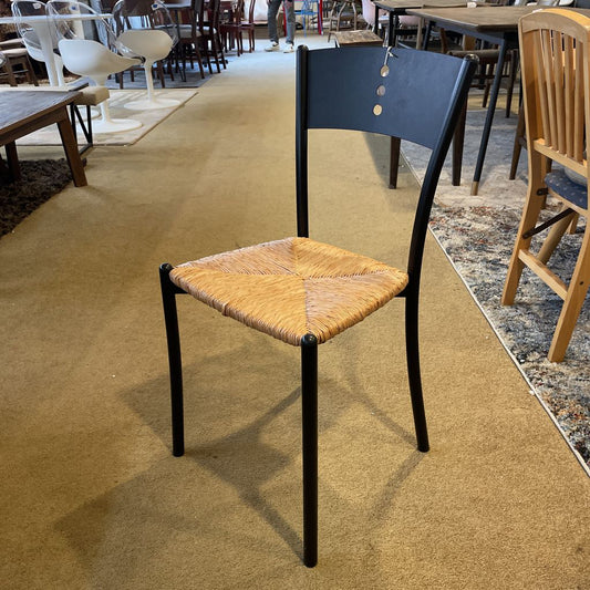Chair with a woven seat and black frame on a carpeted floor