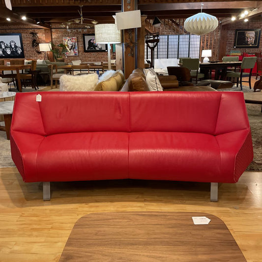 Red sofa in a showroom with wooden flooring and brick walls.