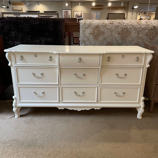 White dresser with multiple drawers in a store setting