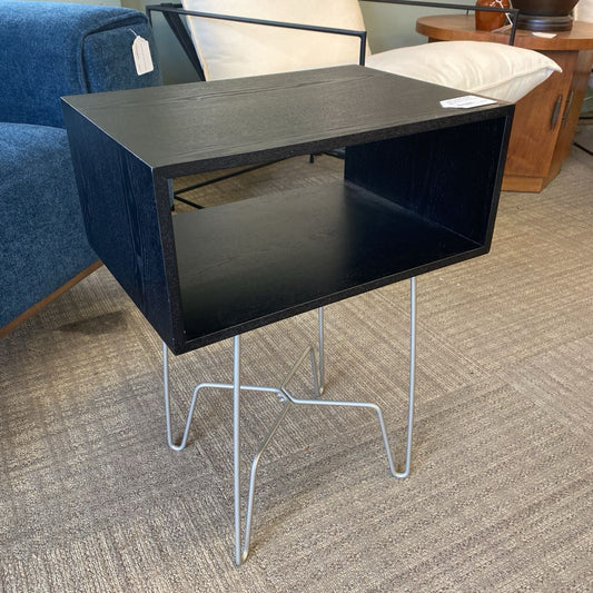 Black side table with metal legs in a room setting