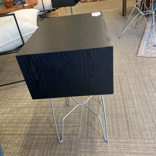 Black textured table with metal legs on a carpeted floor